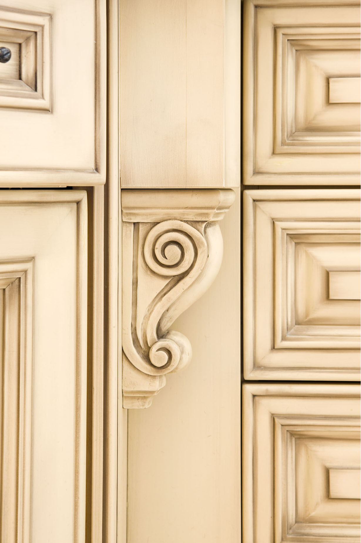 Hand carved details on the corbels jumps to life when the glazing finds its way into the deeper recesses. The same effect is achieved on the ornate mitred doors and drawer fronts. The result is a look of antique furniture as opposed to kitchen cabinets.